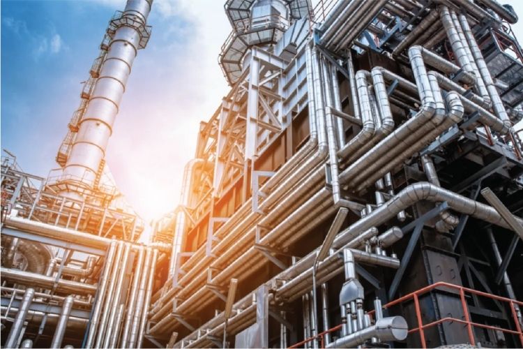 Industrial plant with metal pipes and structures under a bright blue sky.